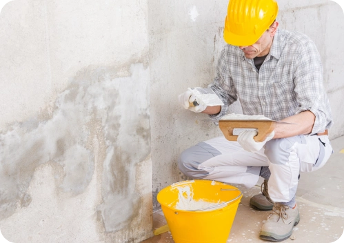 Reparación de Humedades y Filtraciones 15 Trabajador con casco aplicando masilla o revestimiento en pared con manchas de humedad.