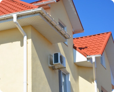 Contrucción de tejados 3 Fachada de casa con tejado rojo y canalones blancos bajo cielo azul.