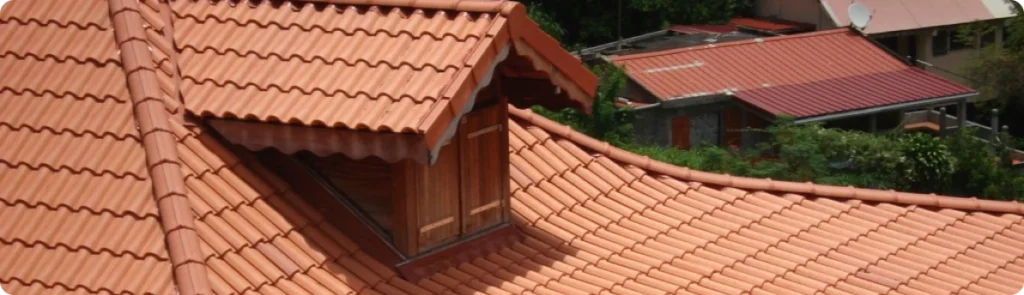 Tejado de teja cerámica en perfecto estado con buhardilla, mostrando la calidad en la instalación de cubiertas en Alcobendas, Madrid.
