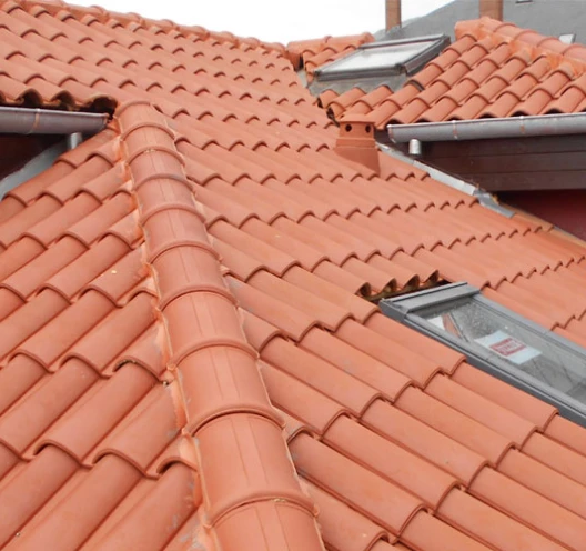 Tejado de tejas de terracota con ventanas de tejado Velux correctamente instaladas y canalones.